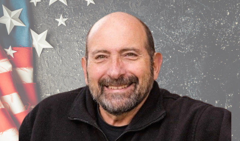 Headshot of Jim Pantelas with a stars and stripe background.