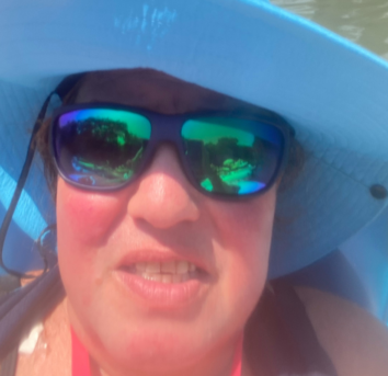 Sherri Eccleston enjoying a beach day with a big blue hat on.